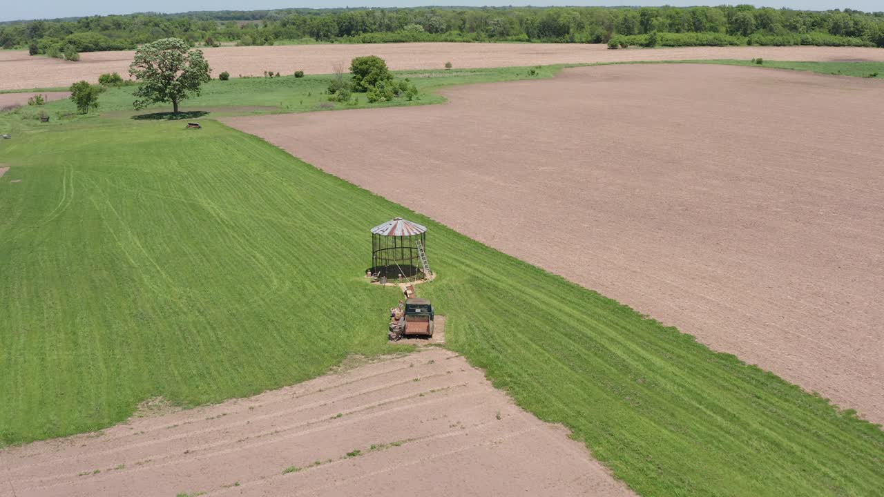 Ampia ripresa aerea in discesa di un silo di grano vuoto e un vecchio camion agricolo nei campi del Minnesota