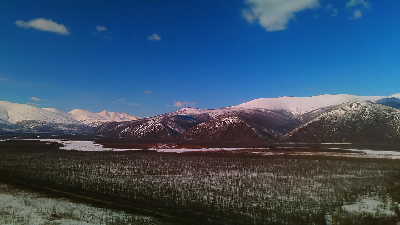 volando un dron sobre las interminables extensiones de la nevada yakutia durante el día con una vista de las montañas 4k