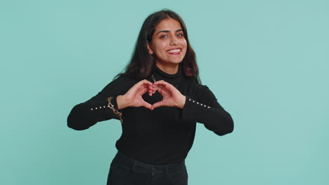 Smiling-indian-woman-makes-heart-gesture-demonstrates-love-sign-expresses-good-feelings-and-sympathy