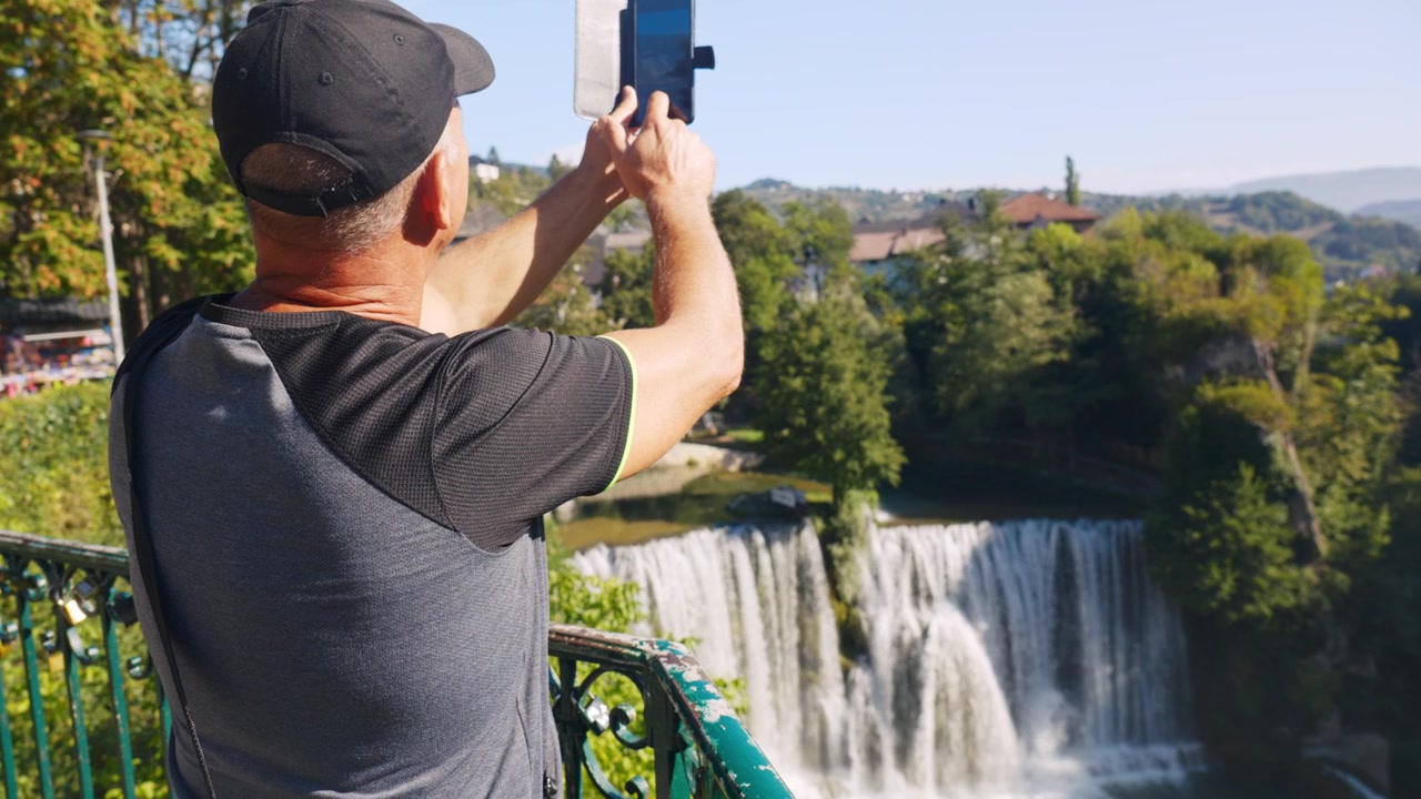 Turista che scatta una foto con il cellulare alla cascata di Pliva a Jajce