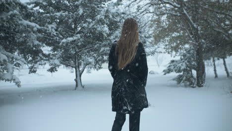 woman walking outside in slow motion, christmas winter snow as snowflakes fall in cinematic slow motion