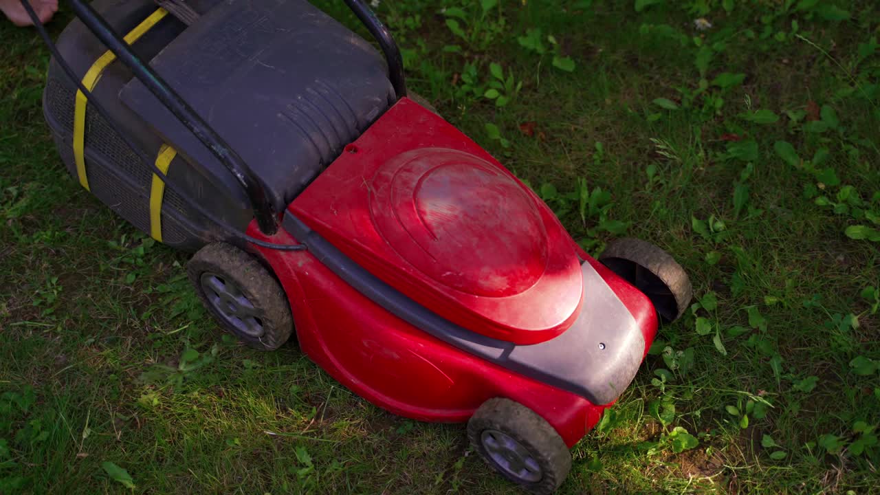 Gardener cuts lawn in garden. Cutting the long grass with lawn mower