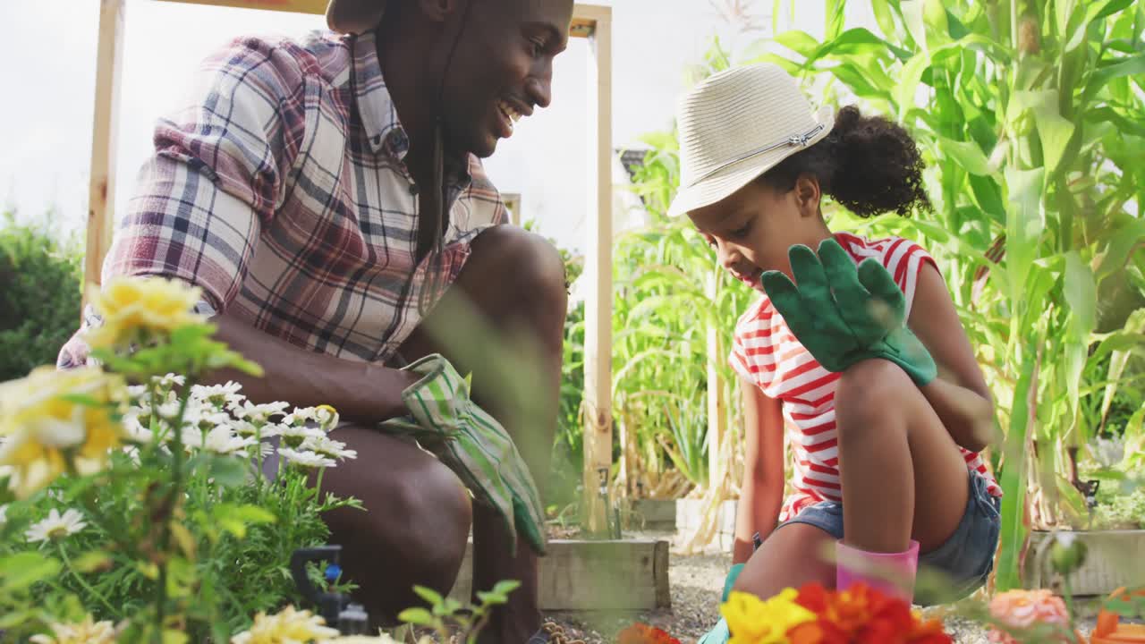 padre y hija afroamericanos jardinería y dando un alto cinco