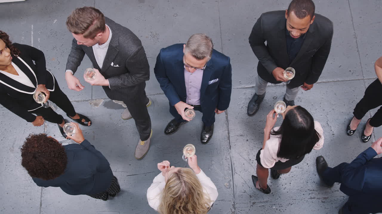 Oversigtsbillede af et forretningsteam, der socialiserer med drinks ved et fyraftensmøde på et moderne kontor.