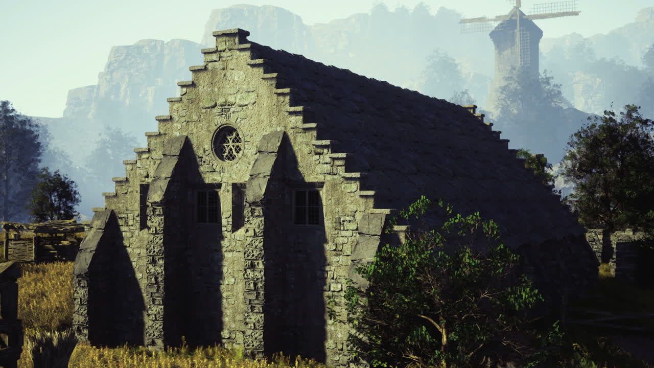 Historic stone building surrounded by nature with a windmill in the background
