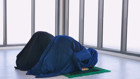 two asian muslim young women in traditional hijab are praying glorify allah and practicing the islamic faith in mosque.
