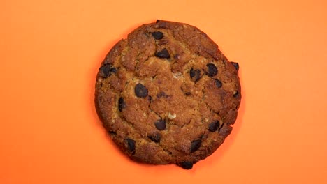 una galleta de chocolate en primer plano, una foto macro, girando rápidamente sobre un fondo naranja giratorio.