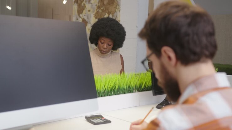 Uomo e donna seduti alle scrivanie vicino ai computer in un ufficio.