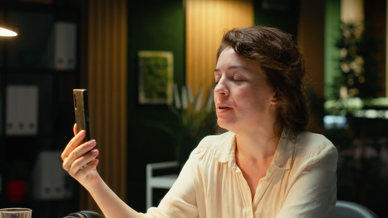 Entrepreneur takes part in a virtual briefing at her workstation with phone