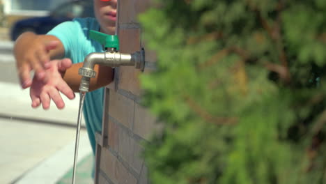 boy washing hands at street tap