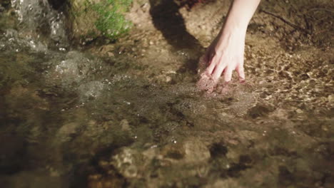 mujer de cultivo tocando el agua que fluye en el río por la noche