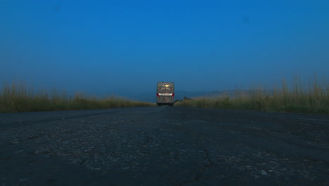 a bus traveling over a camera in the center of a country road