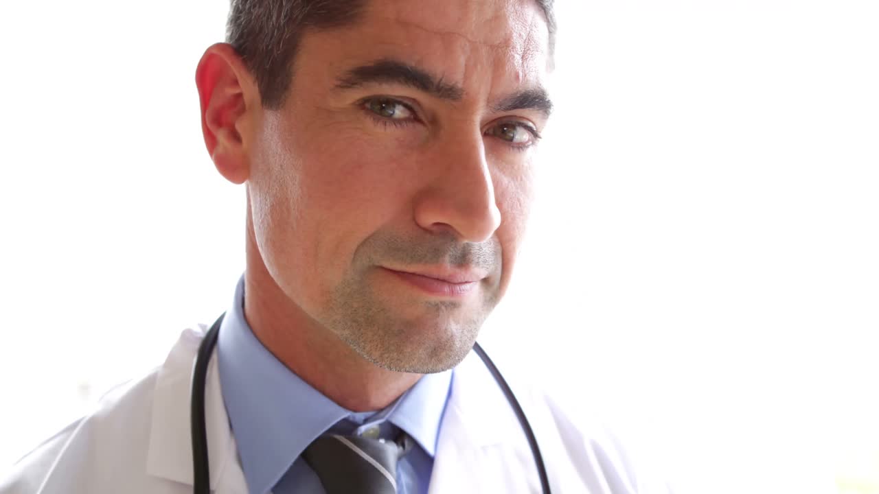 el médico se vuelve a la cámara y sonríe.