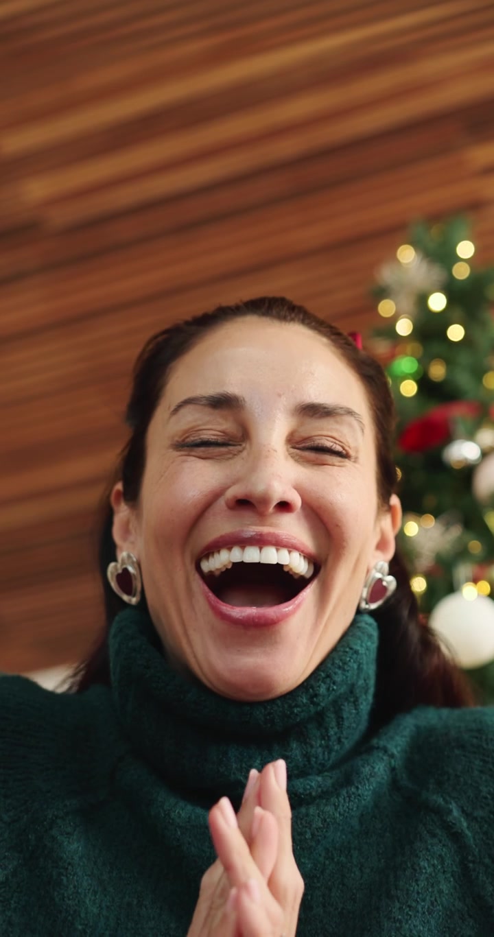 Donna entusiasta che apre un regalo di Natale a casa