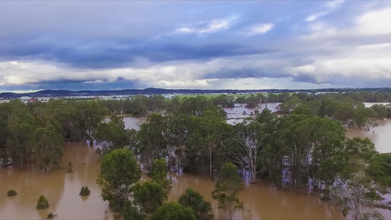 Queensland, NSW, Australia, February floods - stunning aerial drone shot travelling over flooded bushland and over inundated flood plains in Brisbane, under dramatic stromy skies