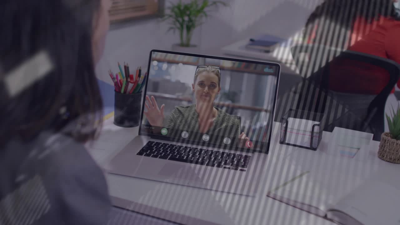 Donna che guarda un laptop mentre un collega da remoto parla, avviando una sovrapposizione di mappa diagonale per aiutare il business