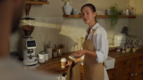 smiling barista handing a customer their coffee and order