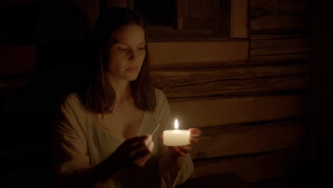 woman lighting a candle in a dark room