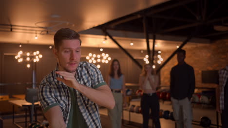 portrait of a young man throwing a bowling ball and knocking out a shooter who jumps and dances with joy in slow motion