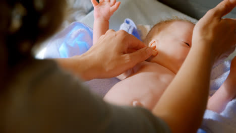 mother giving hand massage to her baby boy at home 4k