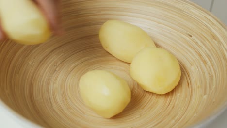 el chef pone papas peladas en un tazón profundo de madera