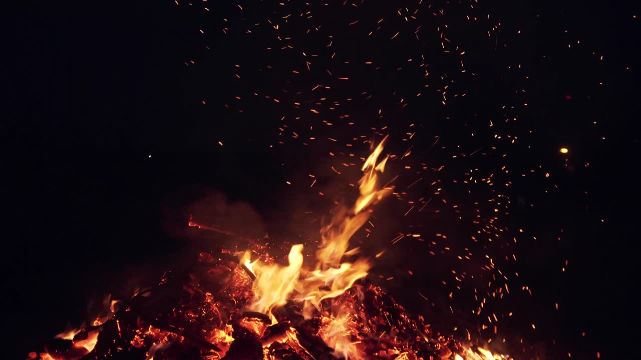 flying hot sparks from a fire in a black sky. turning coal in a fire