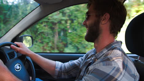 Young-smiling-man-driving-car,-view-from-front-passenger-seat