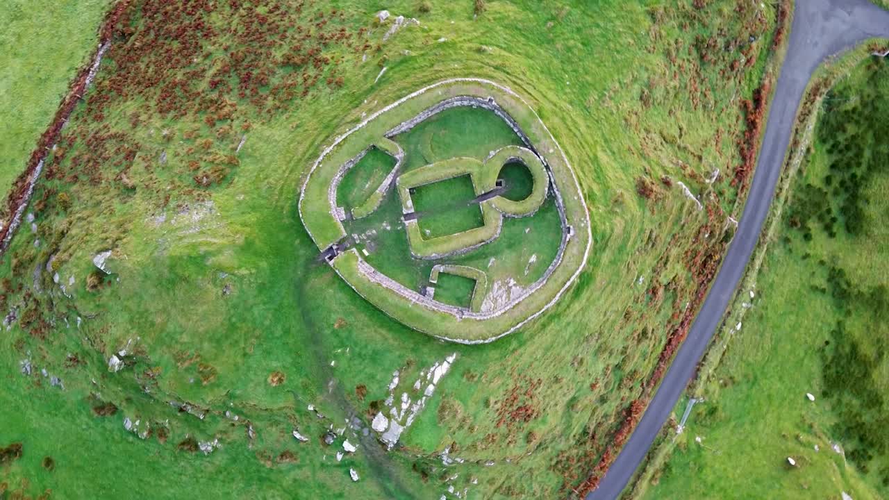 Rekaman drone dari atas berputar di atas Benteng Cincin Leacanabuaile kuno, dinding batu, dan sejarah arkeologi pedesaan Irlandia di Kerry, Irlandia.