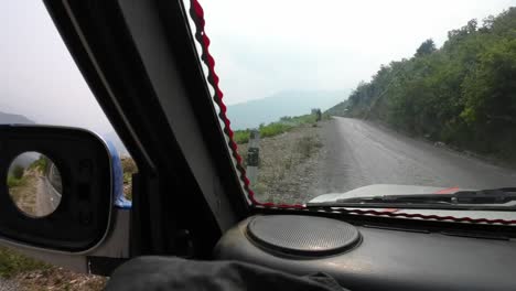 pov jeep ride through nepal's rugged interior. driving on a windy mountain road. bus coming towards
