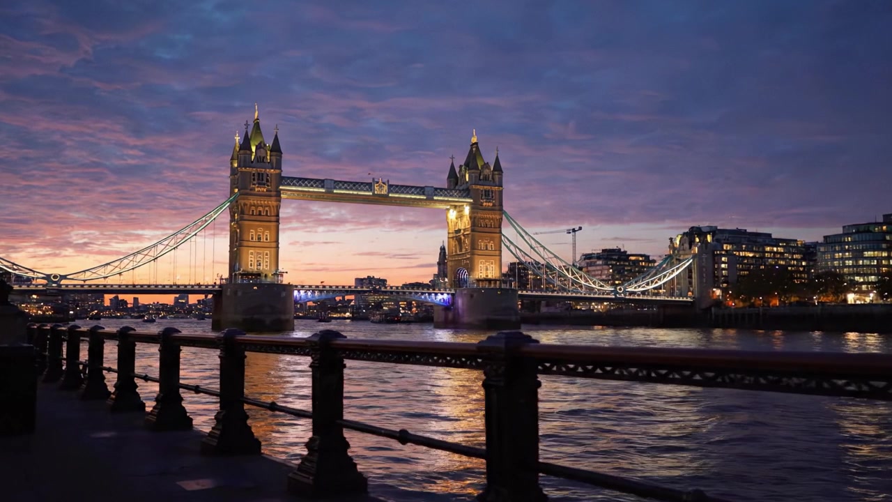 Viste serali mozzafiato: il Tower Bridge illuminato dai colori del tramonto sul fiume Tamigi in un sereno contesto urbano