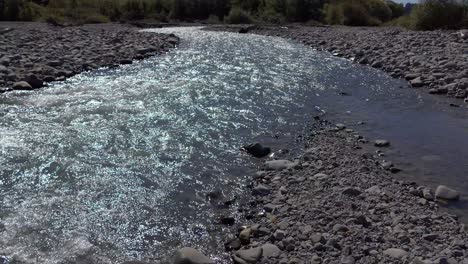 Sunshine-falls-on-steadily-flowing-river-as-it-curves-away---Kowai-River,-Canterbury