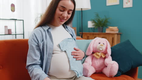 pregnant woman looking at baby cloth and pacifier preparing pregnancy expecting baby childbirth