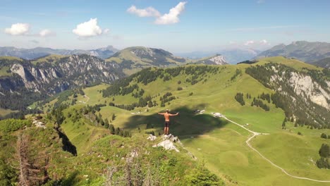 a man is standing topless alone by himself in the sun overlooking the amazing landscape, reaching his arms high up into the sky in success and accomplishment