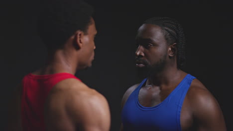 cerca de dos boxeadores masculinos que se enfrentan cara a cara antes de un partido de boxeo mirando fijamente a su oponente contra un fondo negro 1