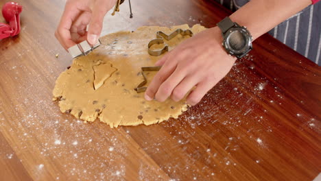 biracial man wcutting christmas cookies in kitchen at home, slow motion