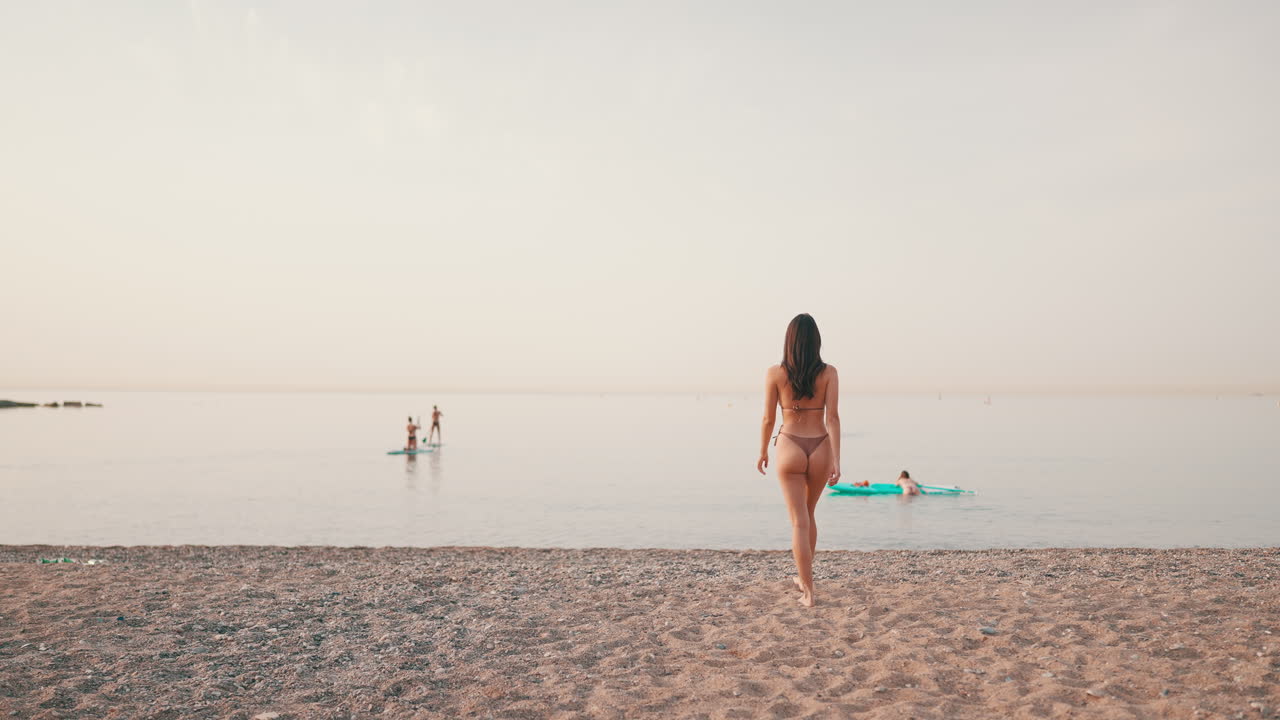 Woman in bikini walking on a sandy beach