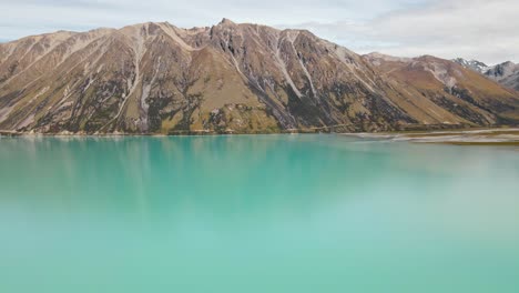 aerial footage of majestic mountain reflecting in turquoise lake water in new zealand