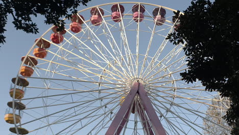 colorful ferris wheel moving at amusement park with trees and copy space