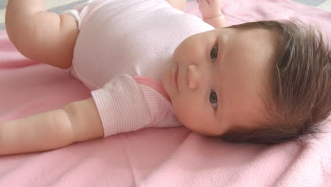 Baby-Girl-Laying-On-Pink-Blanket-Shot-In-Slow-Motion