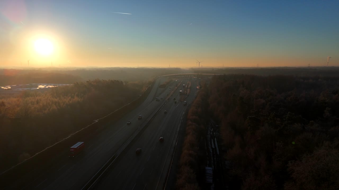 Sunrise during cold winter day on american highway. Aerial top down flyover. Leafless colored trees during cold day in USA. Forward wide shot.
