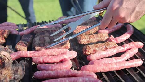 people grilling sausages on griller using fork and tongs