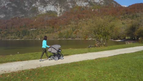 young mother pushing baby stroller on a dirt road by the bohinj lake, slovenia