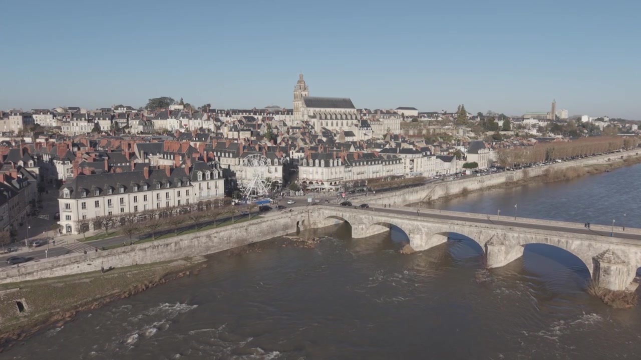 Una vista aerea mostra Blois con la sua guglia della cattedrale e il ponte in pietra che attraversa il fiume Loira sottostante.