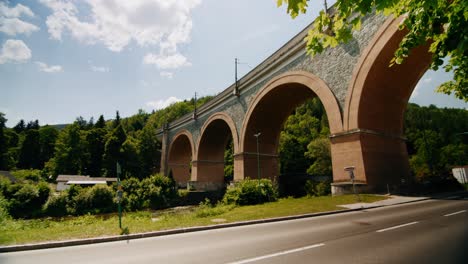 viaduct schwarza with motorcycles and cars driving by in the foreground and trees covering up the right side of the viaduct