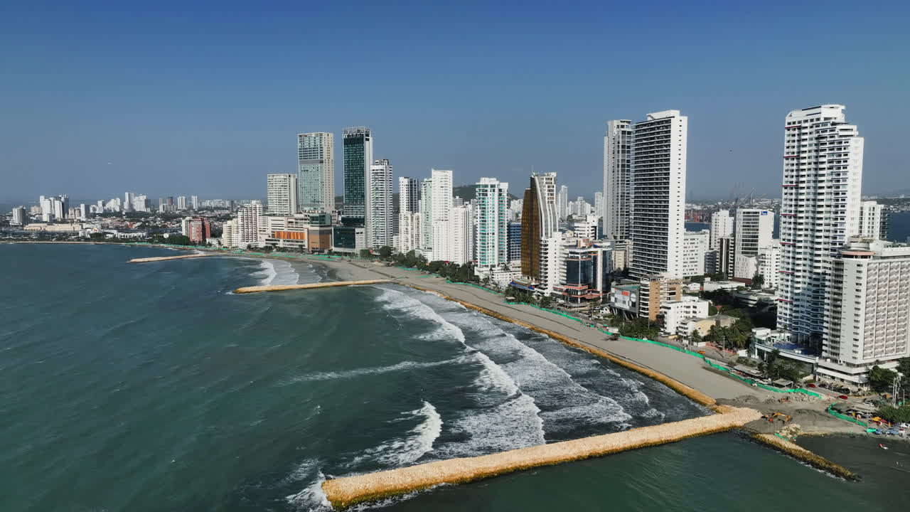 disparo de drones frente a la playa de bocagrande y el horizonte, día soleado en cartagena, colombia