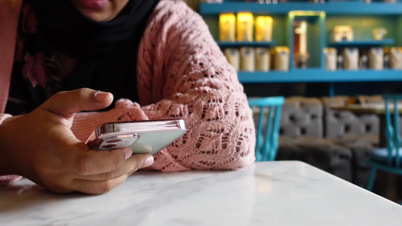Wanita menggunakan ponsel di kafe