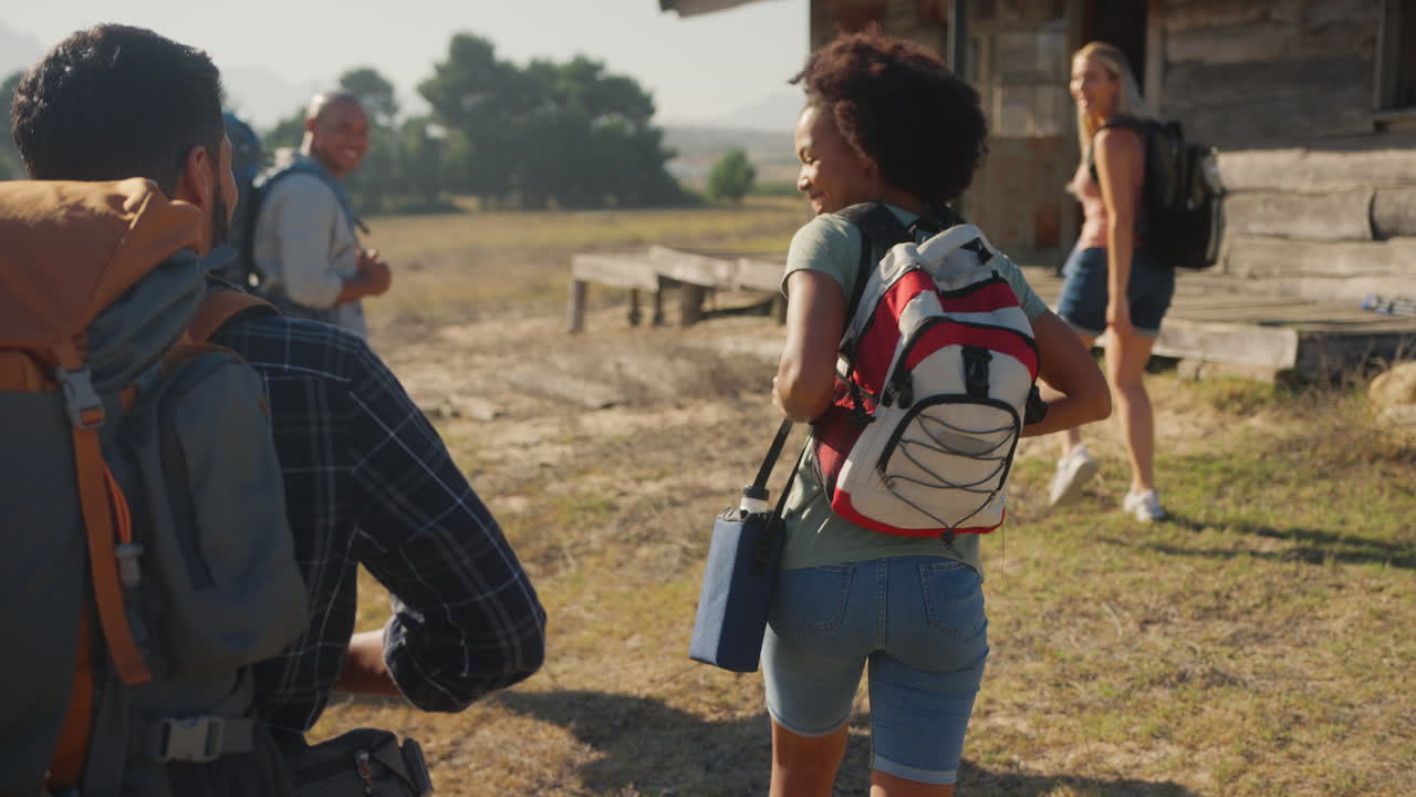 vista trasera de un grupo de amigos con mochilas caminando juntos en el campo