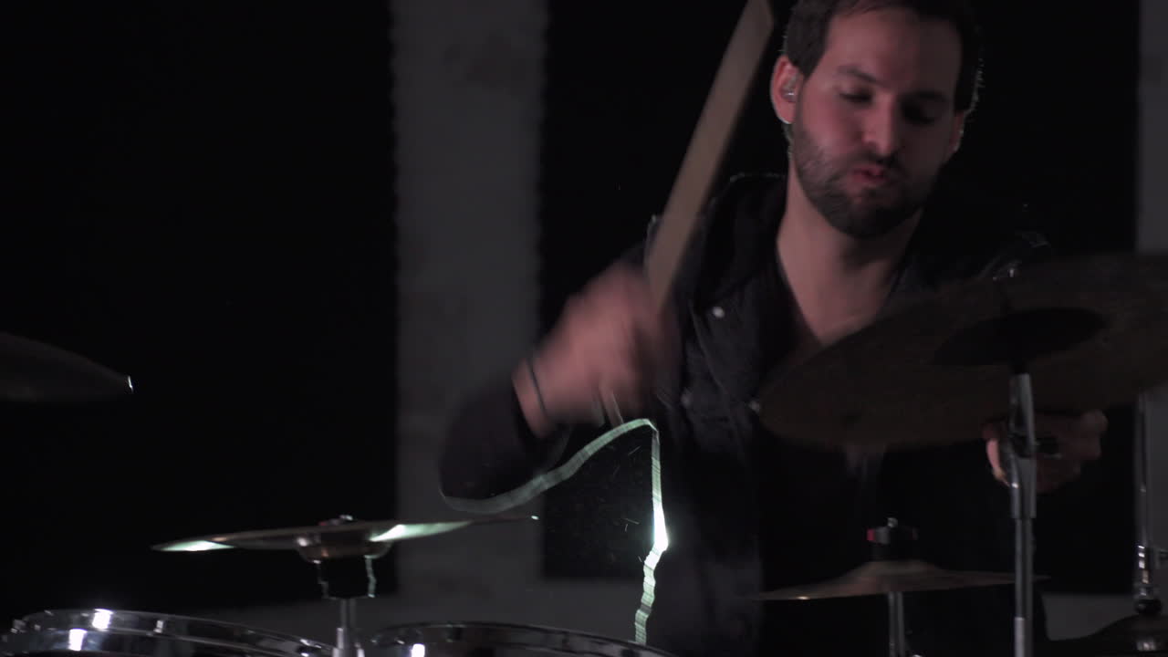 A close up of a young heavy metal drummer rehearsing his songs and doing some stick tricks