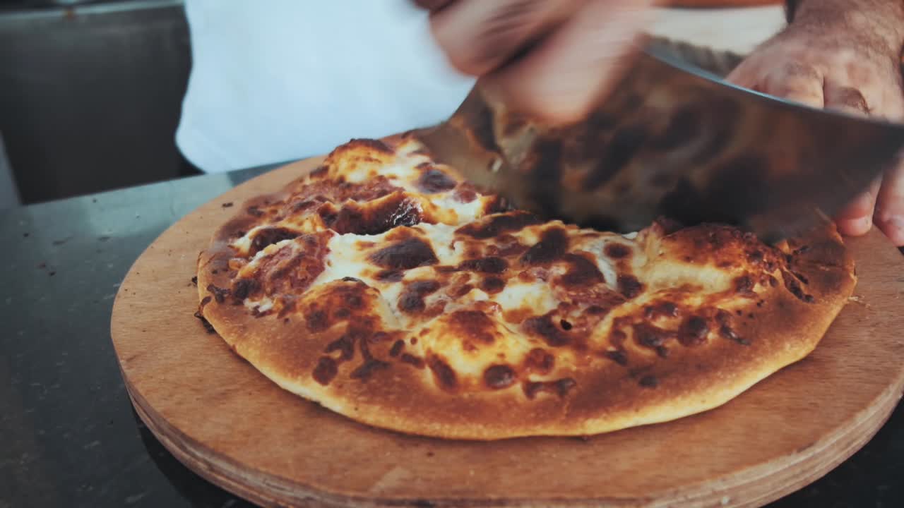 남자는 피자 커터를 사용하여 피자를 잘라