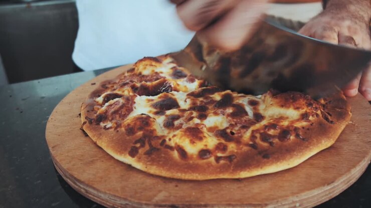 Uomo taglia la pizza con un tagliapizza